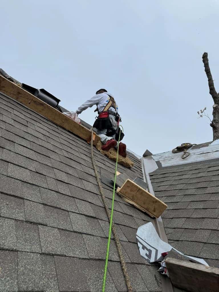 Work boots planted on architectural shingles during an install